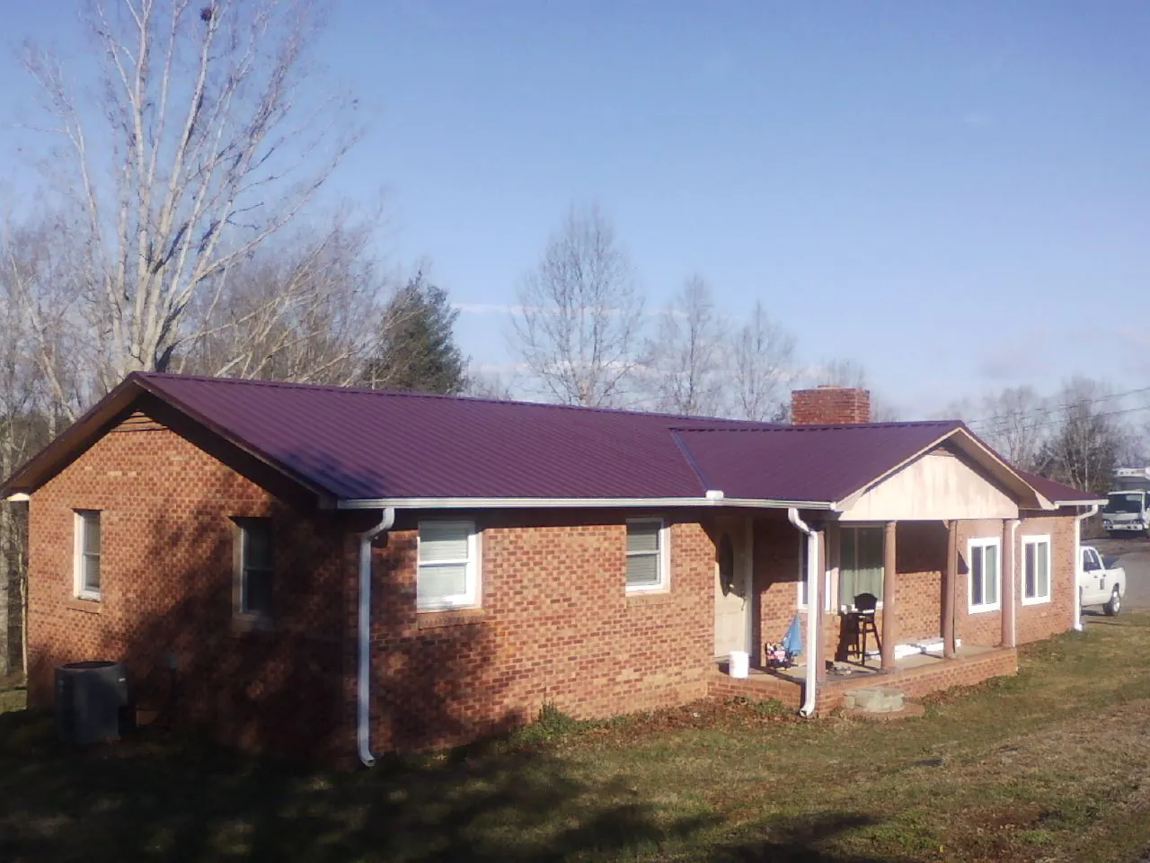 Burgundy metal roof on a brick ranch home with a new addition in Belle Chasse