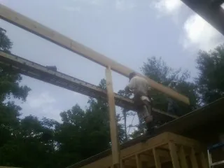 Carpenter setting a ridge beam over a new addition frame — Ice Dam Removal by Roofing Brothers in Belle Chasse