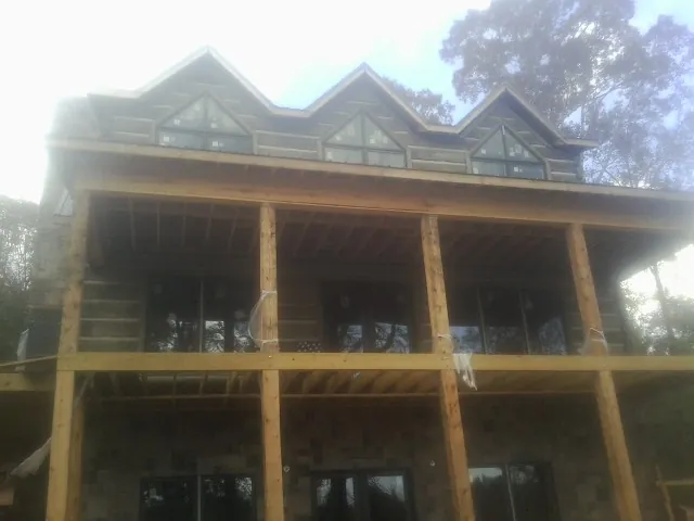 Dormers and porch framing on a large log home under construction — Roof Coating work by our crew in Belle Chasse