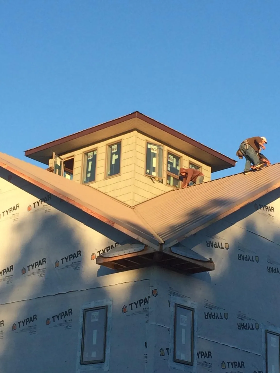 Roofers working around a rooftop cupola on a new metal roof at sunset — Roof Waterproofing in Belle Chasse by Roofing Brothers